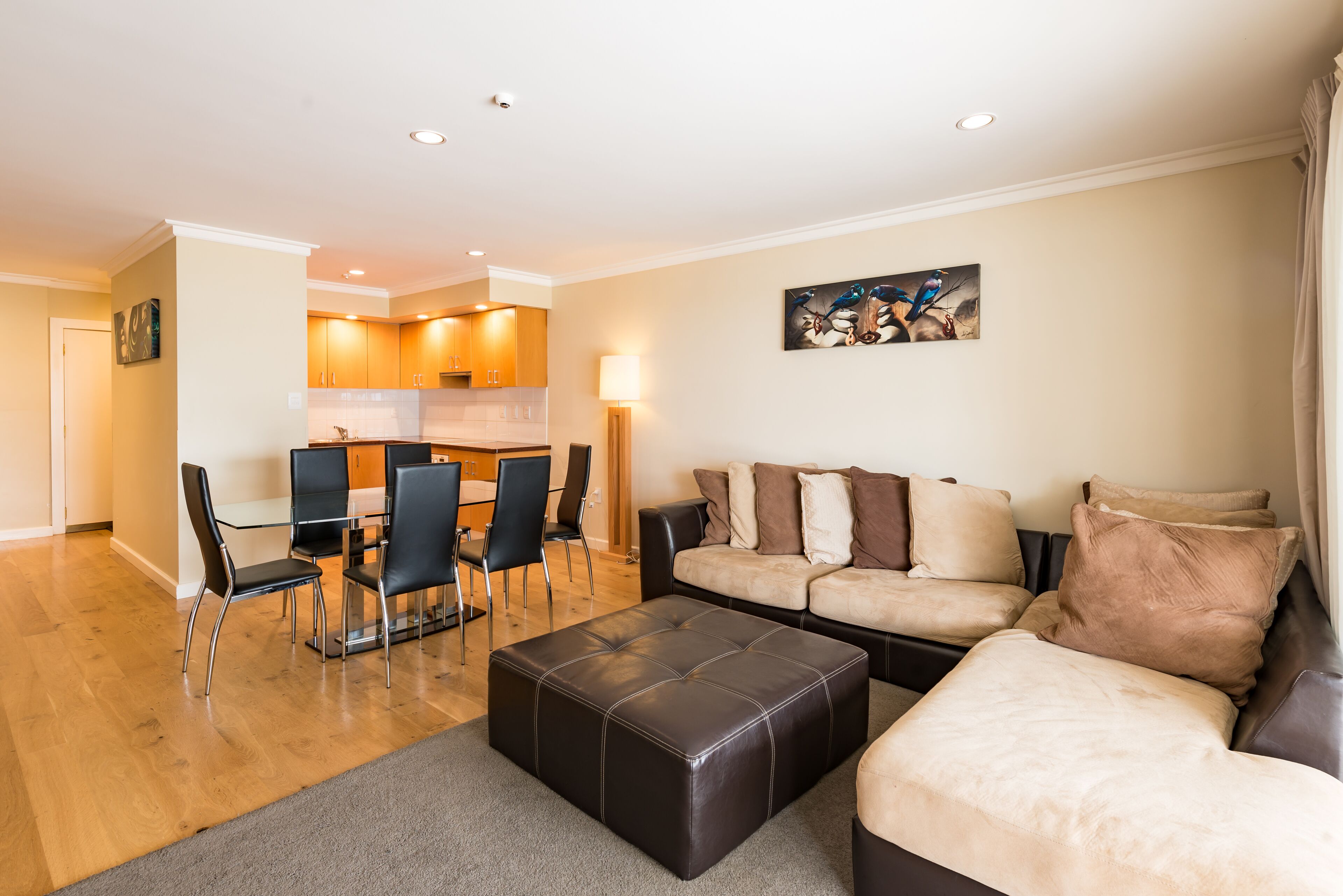 A modern living room with a sofa, ottoman, and dining area with chairs and a table.