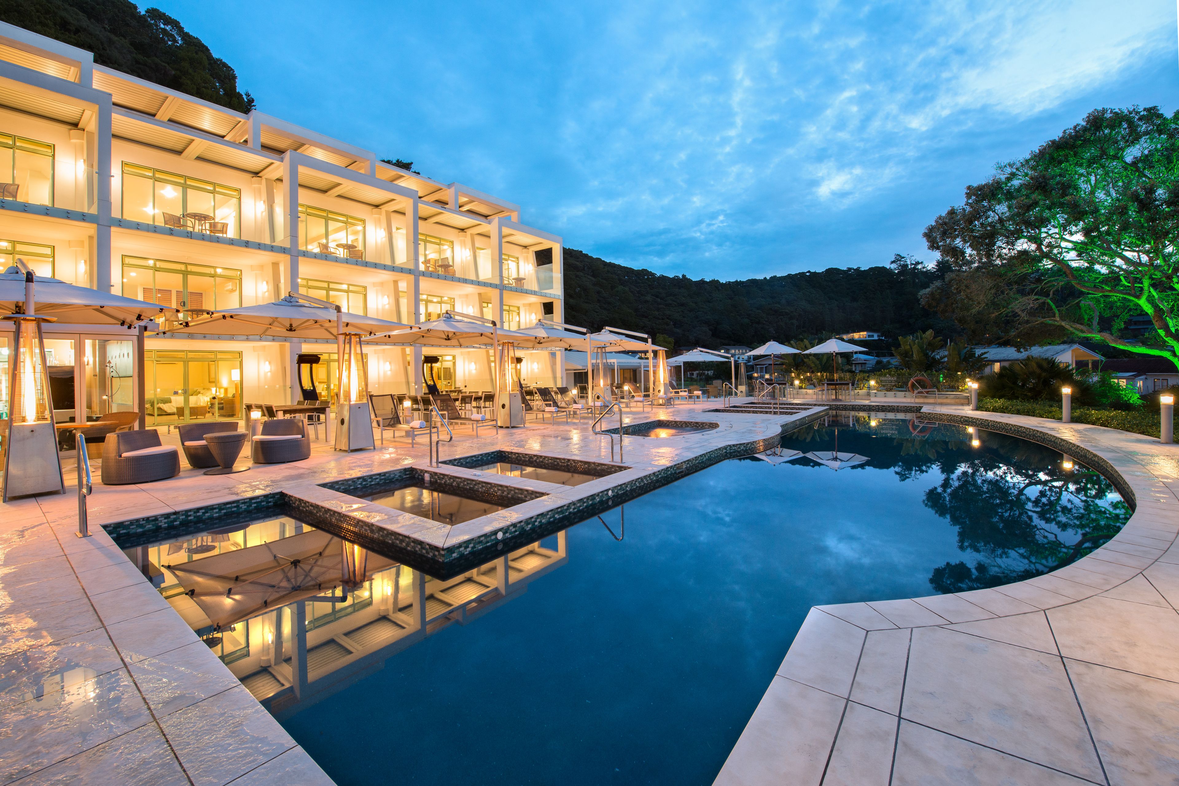 Ein modernes Hotel mit Poolbereich, Sitzgelegenheiten im Freien und Blick auf die umliegende Landschaft.
