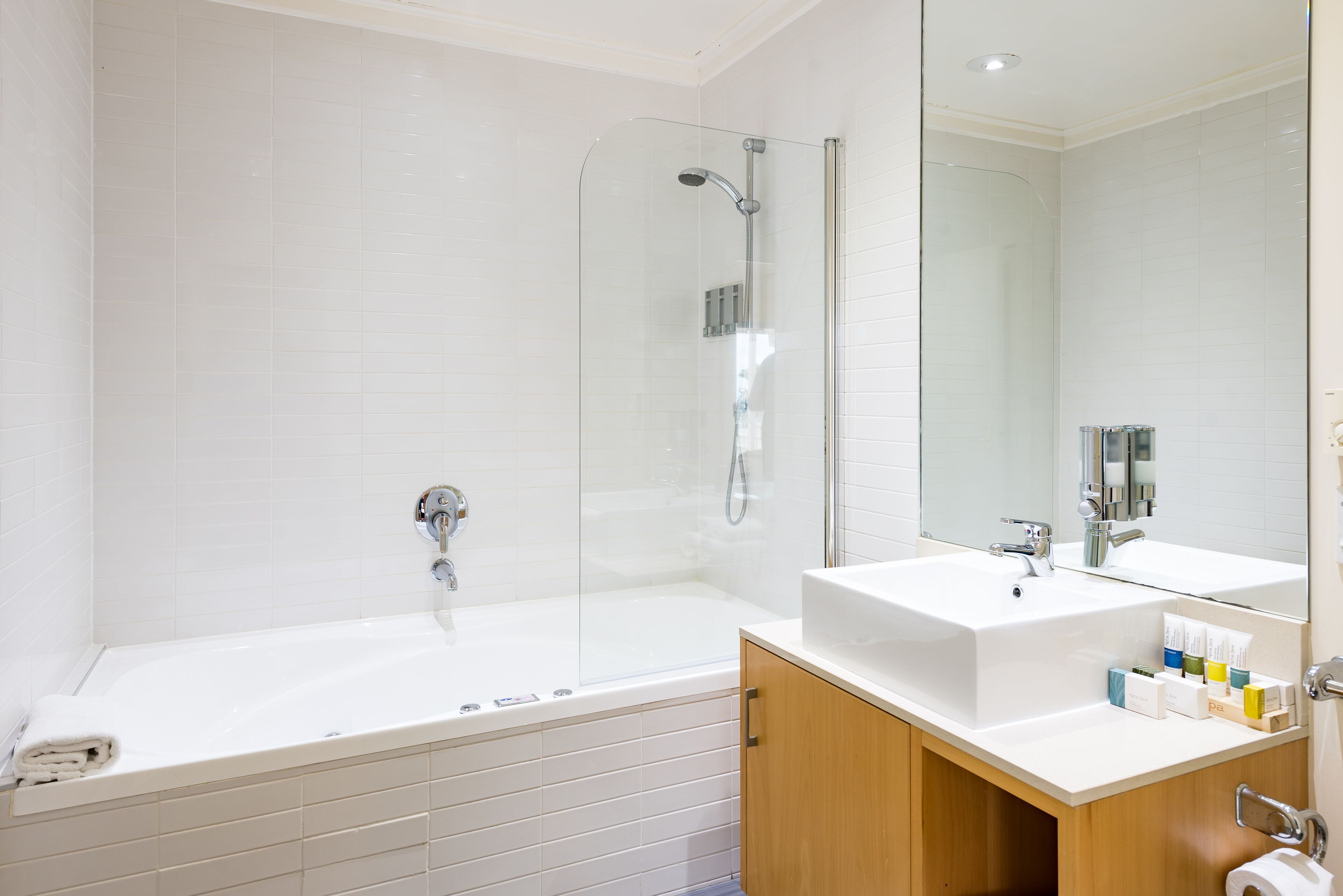 A modern bathroom with a glass-enclosed shower, a large bathtub, and a vanity with a mirror.