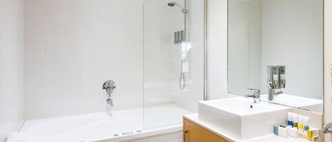 A modern bathroom with a glass-enclosed shower, a large bathtub, and a vanity with a mirror.