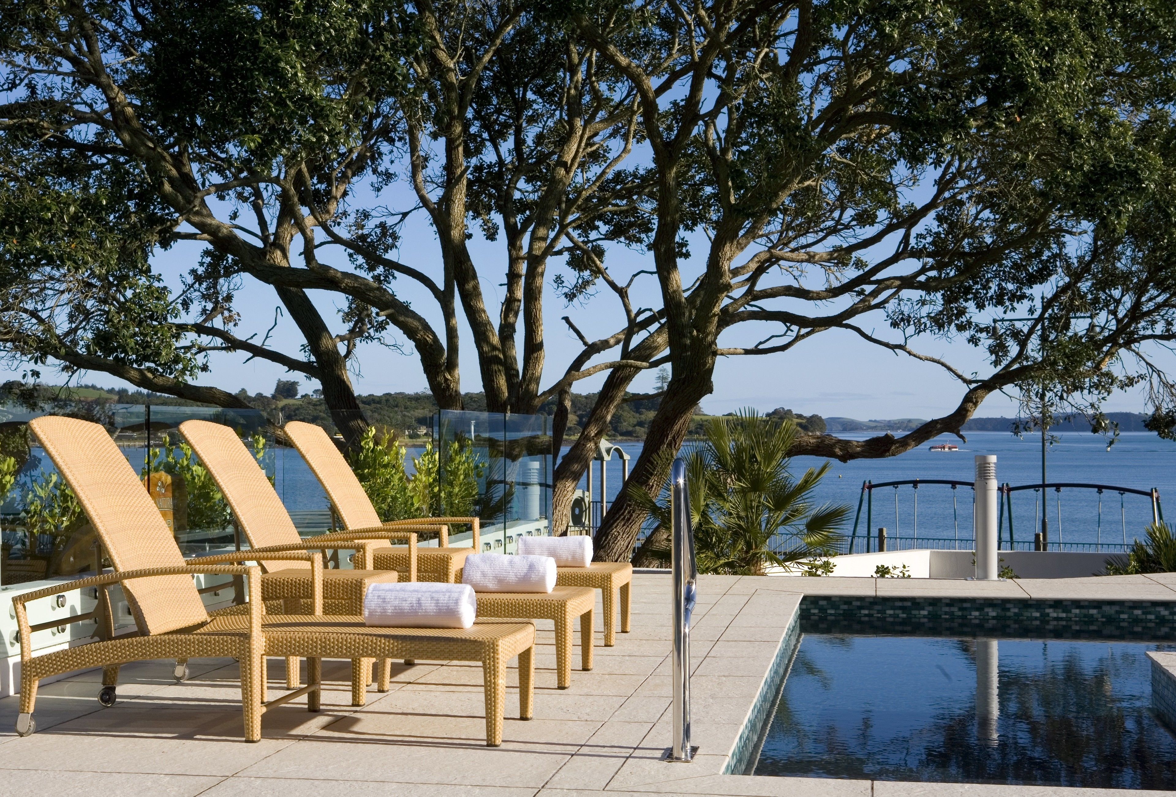 A poolside area with lounge chairs and a view of the sea.