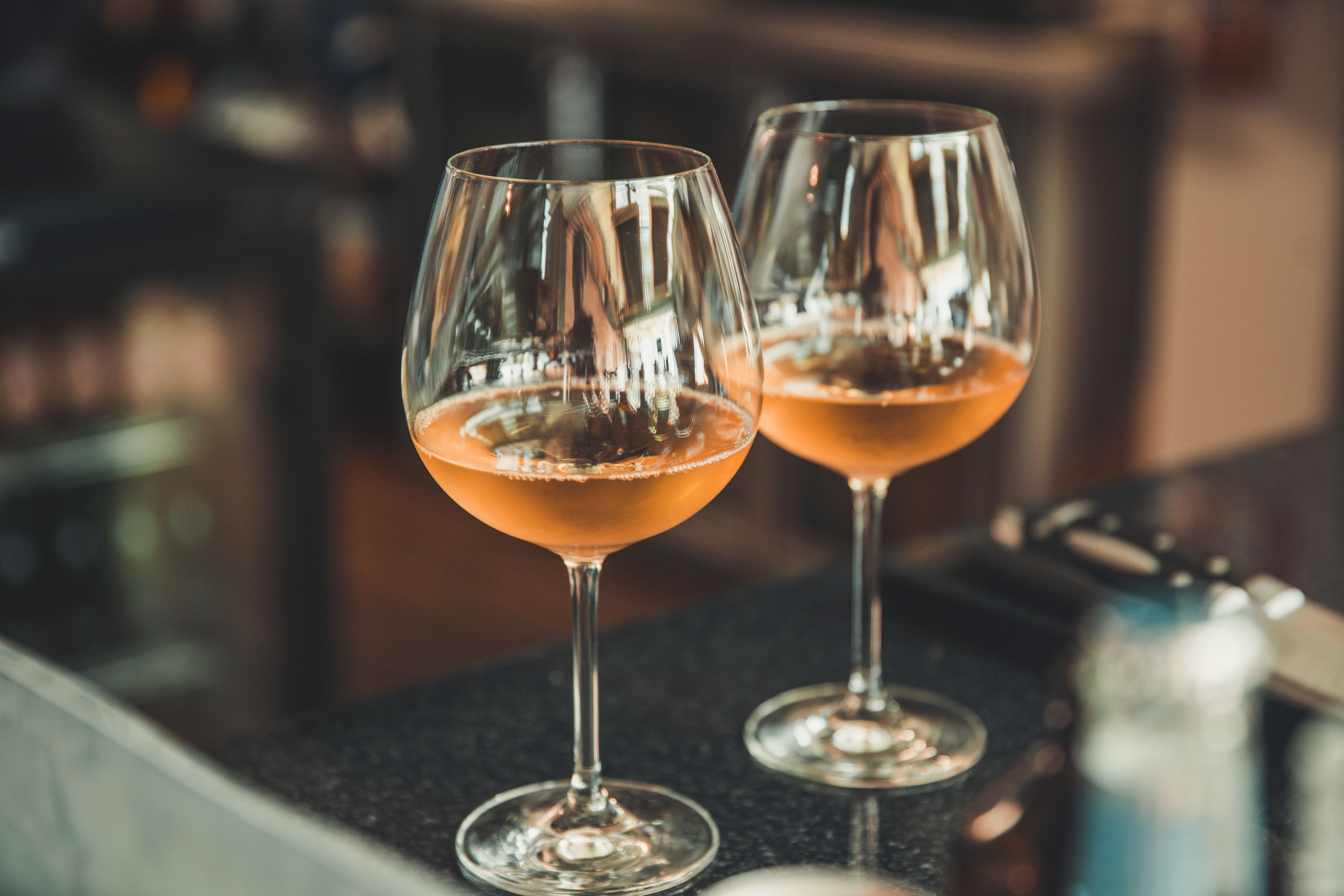 Two glasses of a pinkish beverage on a bar counter.