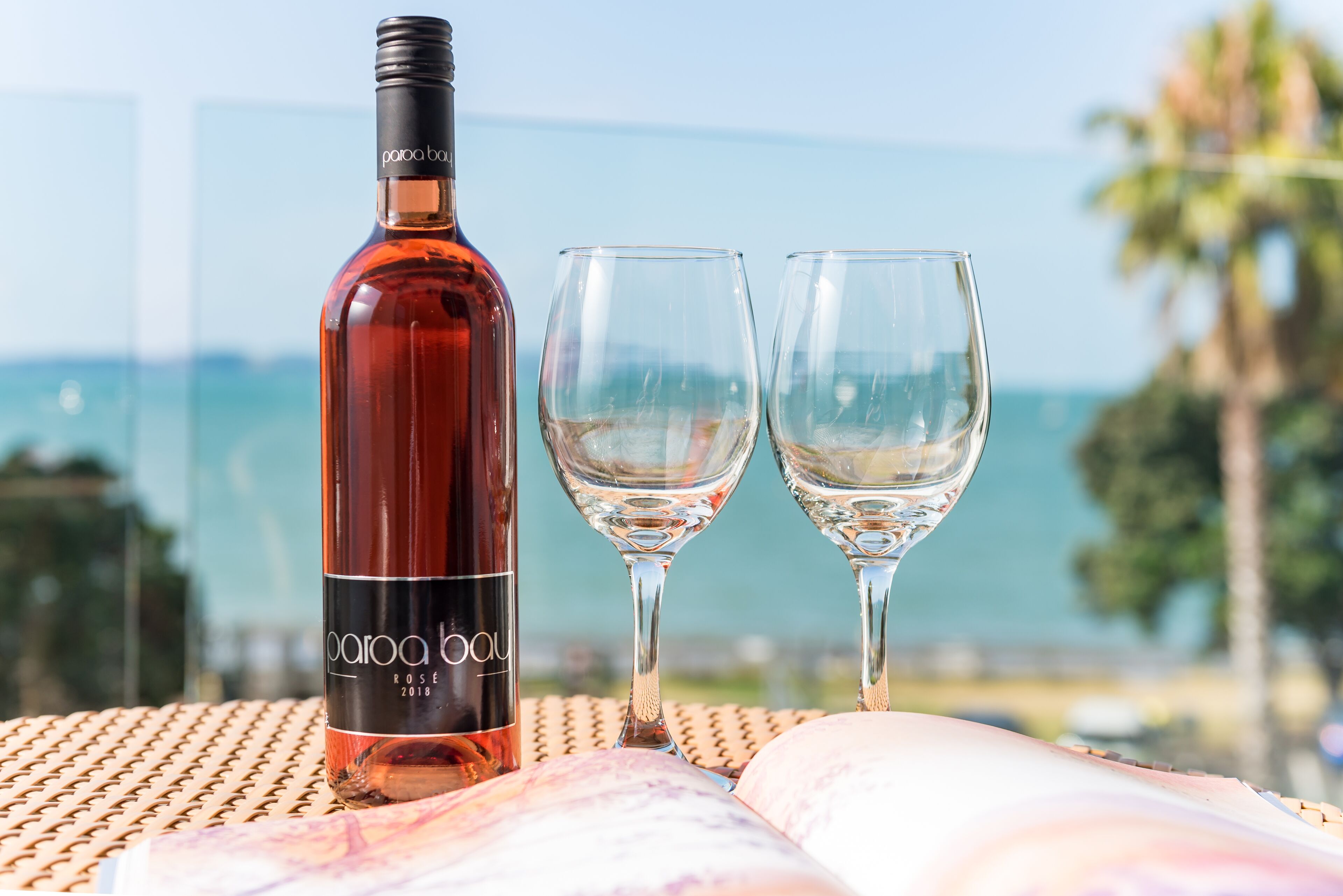 Eine Flasche Caroà Boul Wein und zwei Gläser auf einem Tisch mit Blick auf den Ozean.