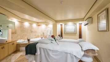 Relax in a serene spa room with a massage table, sink, and large mirror.