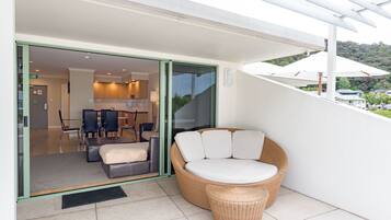 A modern outdoor seating area with a wicker sofa and a glass door leading to a dining area.