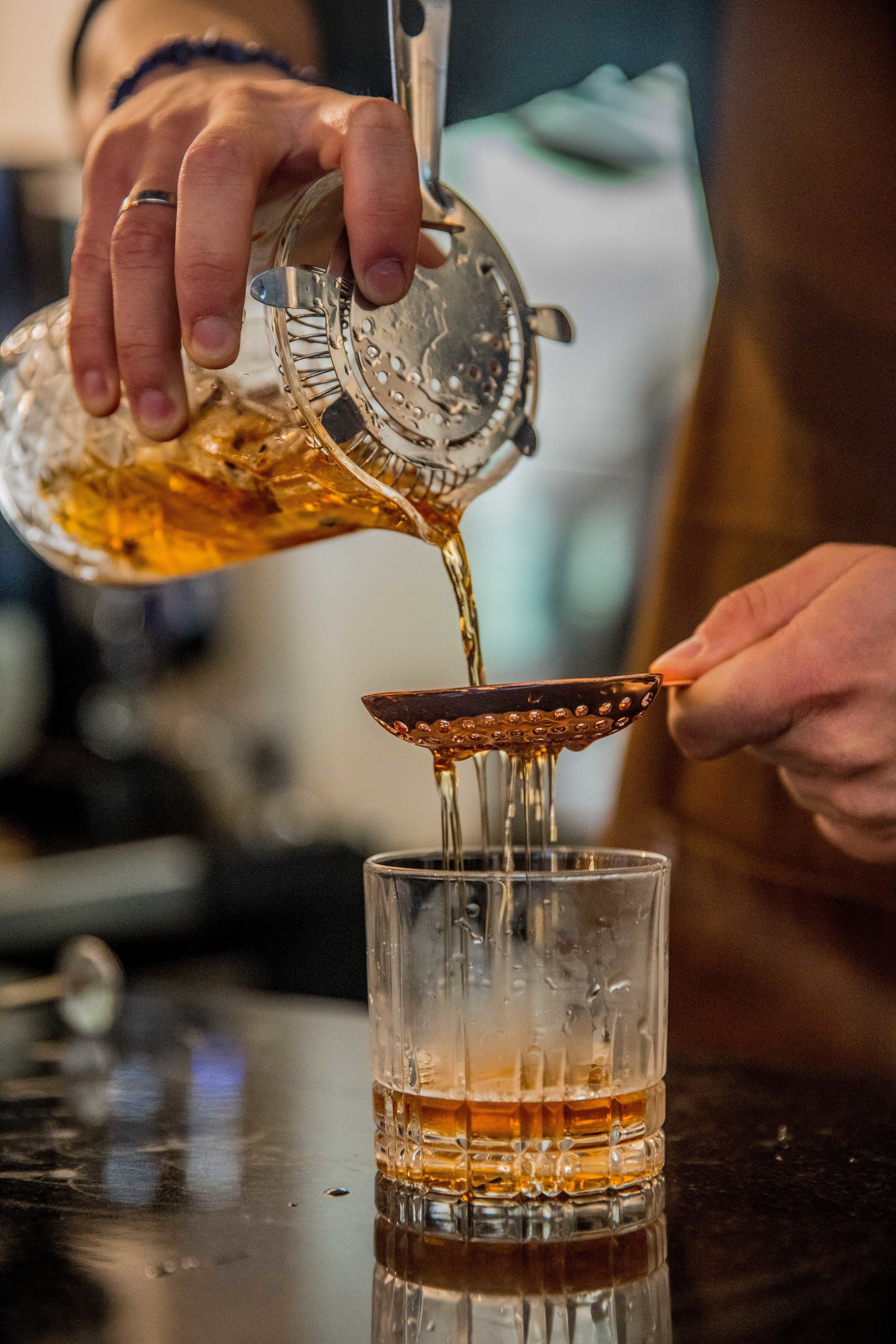 A person pouring a golden liquid into a glass.