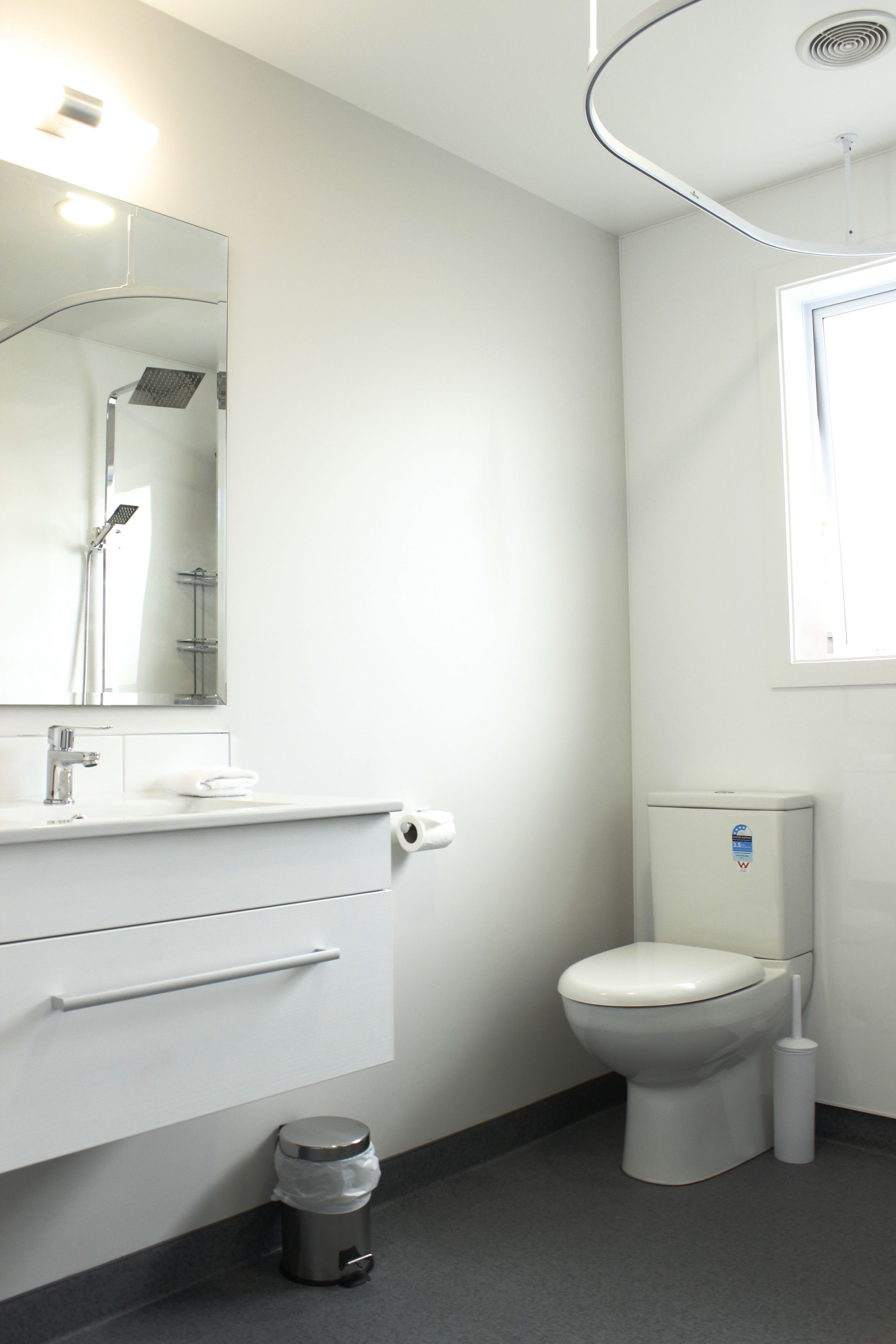 A modern bathroom with a white sink, mirror, and toilet.