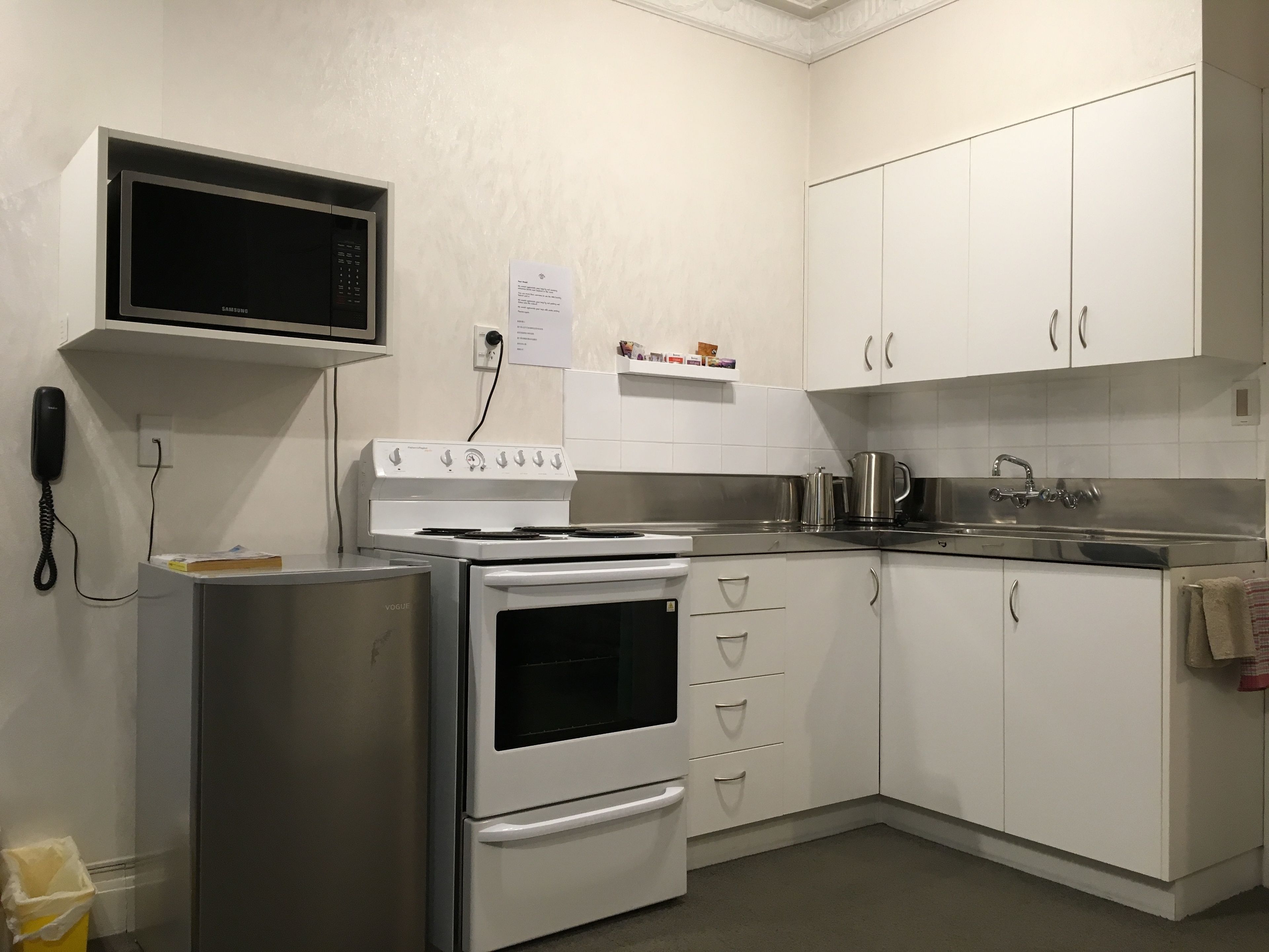 A kitchen with white cabinets, a microwave, a stove, and a sink.