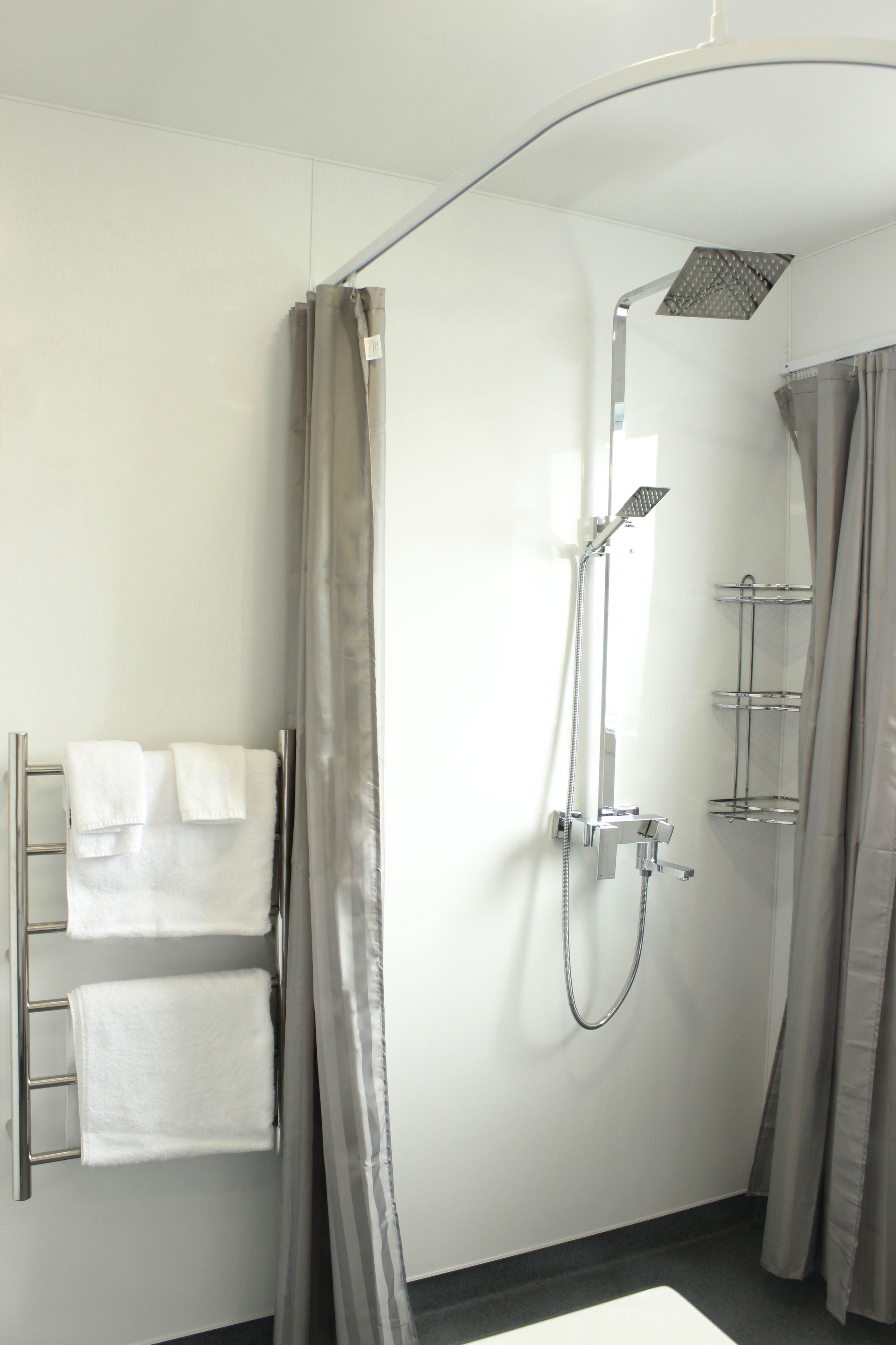 Un baño moderno con ducha a ras de suelo, toallero y mampara de vidrio.