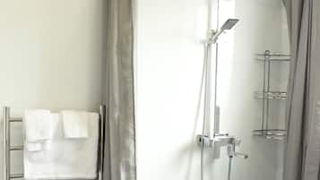 Un baño moderno con ducha a ras de suelo, toallero y mampara de vidrio.
