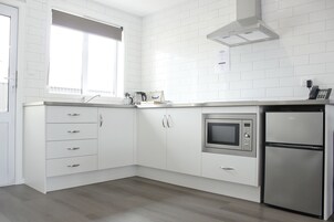 Una cocina moderna con armarios blancos, horno empotrado y refrigerador.