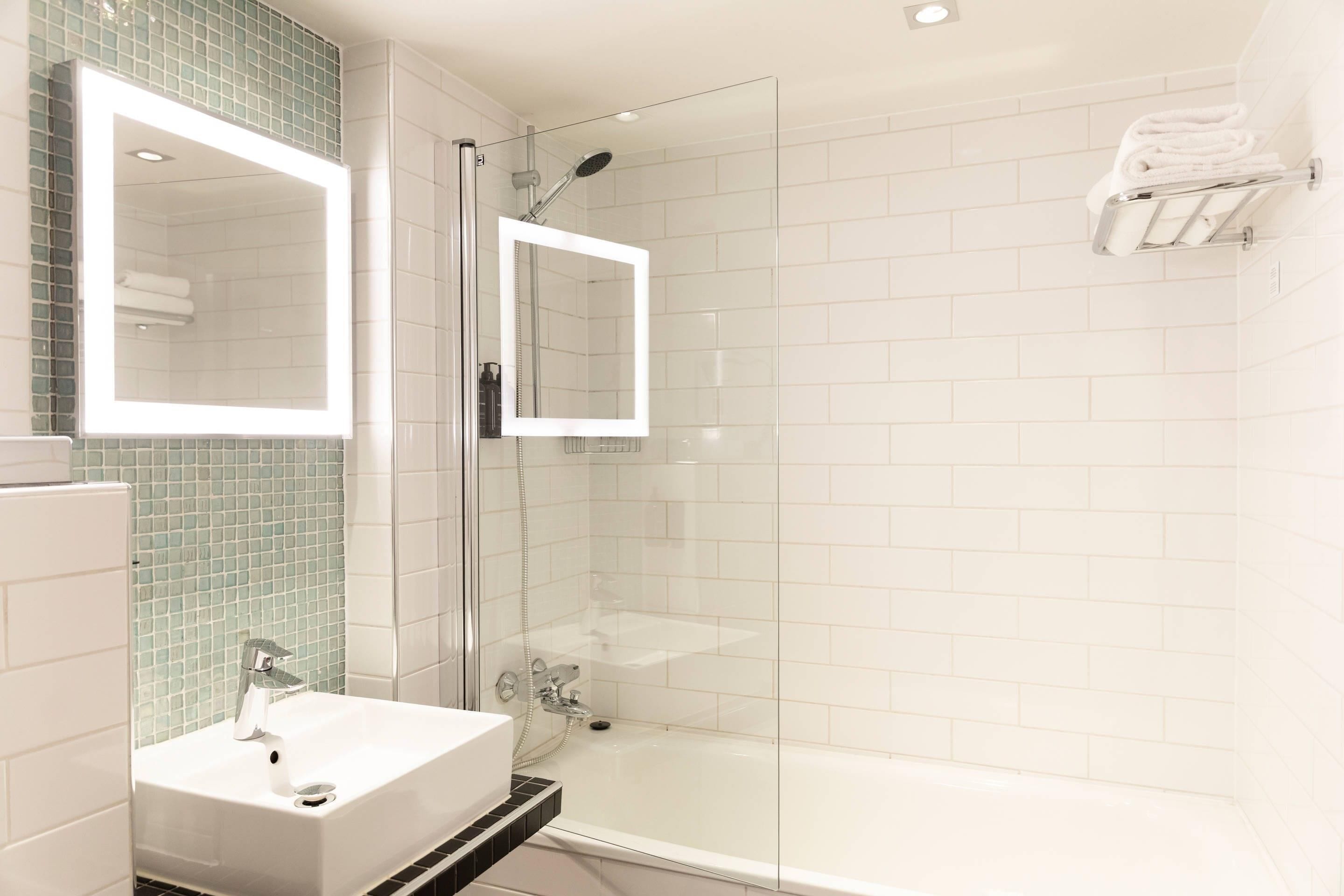 A modern bathroom with a glass-enclosed shower, a white sink, and a mirror.