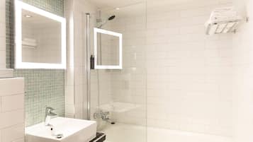A modern bathroom with a glass-enclosed shower, a white sink, and a mirror.