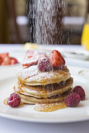 Ein Stapel Pfannkuchen mit Erdbeeren und Himbeeren auf einem weißen Teller.