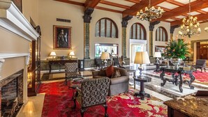Un amplio vestíbulo con una chimenea imponente, muebles elegantes y un candelabro.