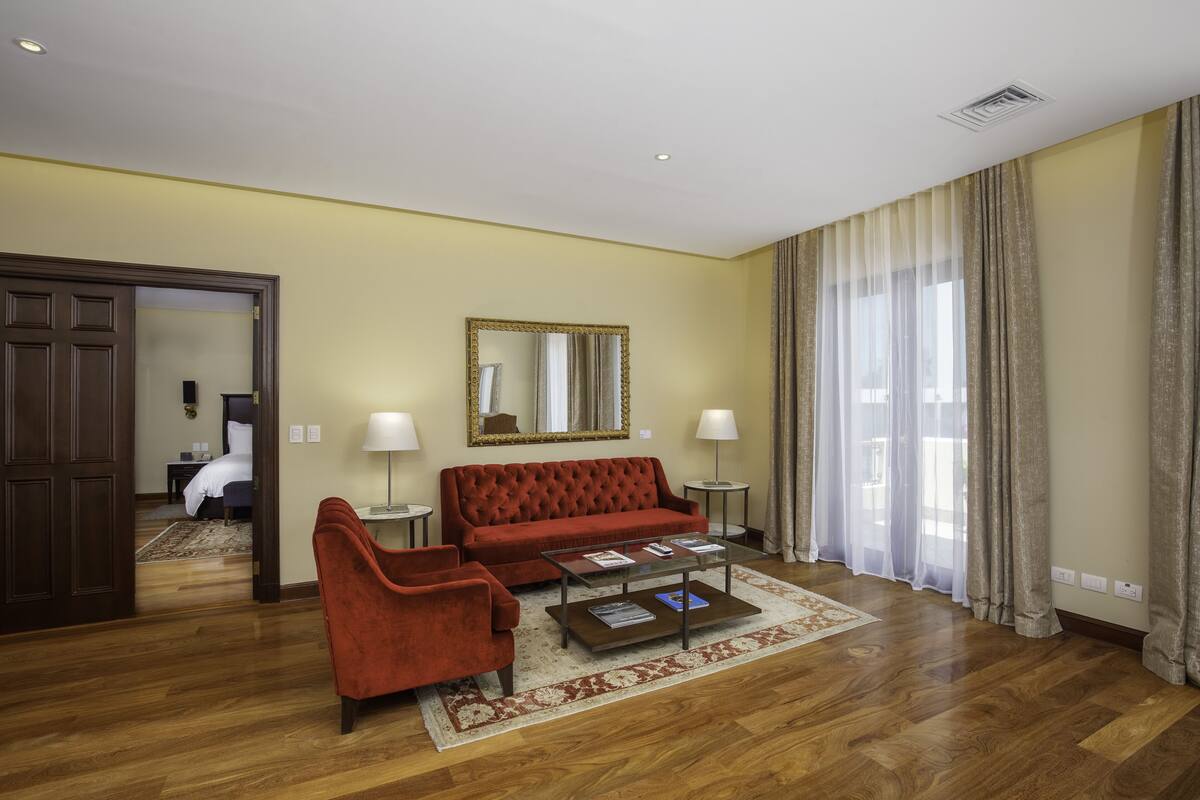 Ein Hotelzimmer mit einem roten Sofa, einem Glastisch und einem großen Spiegel an der Wand.