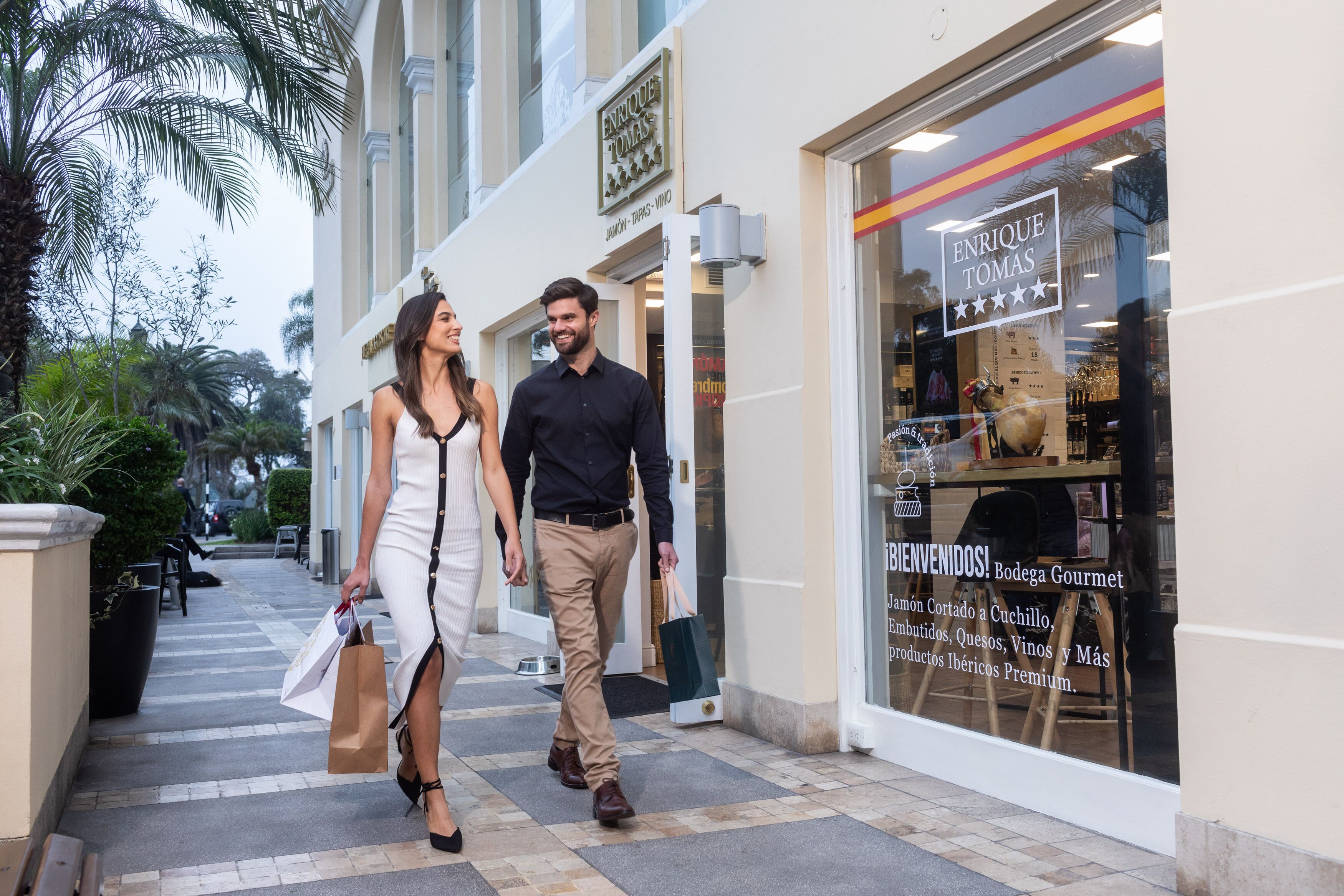 A couple walking on a sidewalk in front of a building with a storefront.
