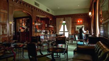 A spacious lobby with wooden paneling, leather seating, and a bar area.