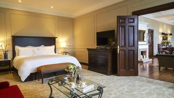 A hotel room with a large bed, a TV, a coffee table, and a fireplace.