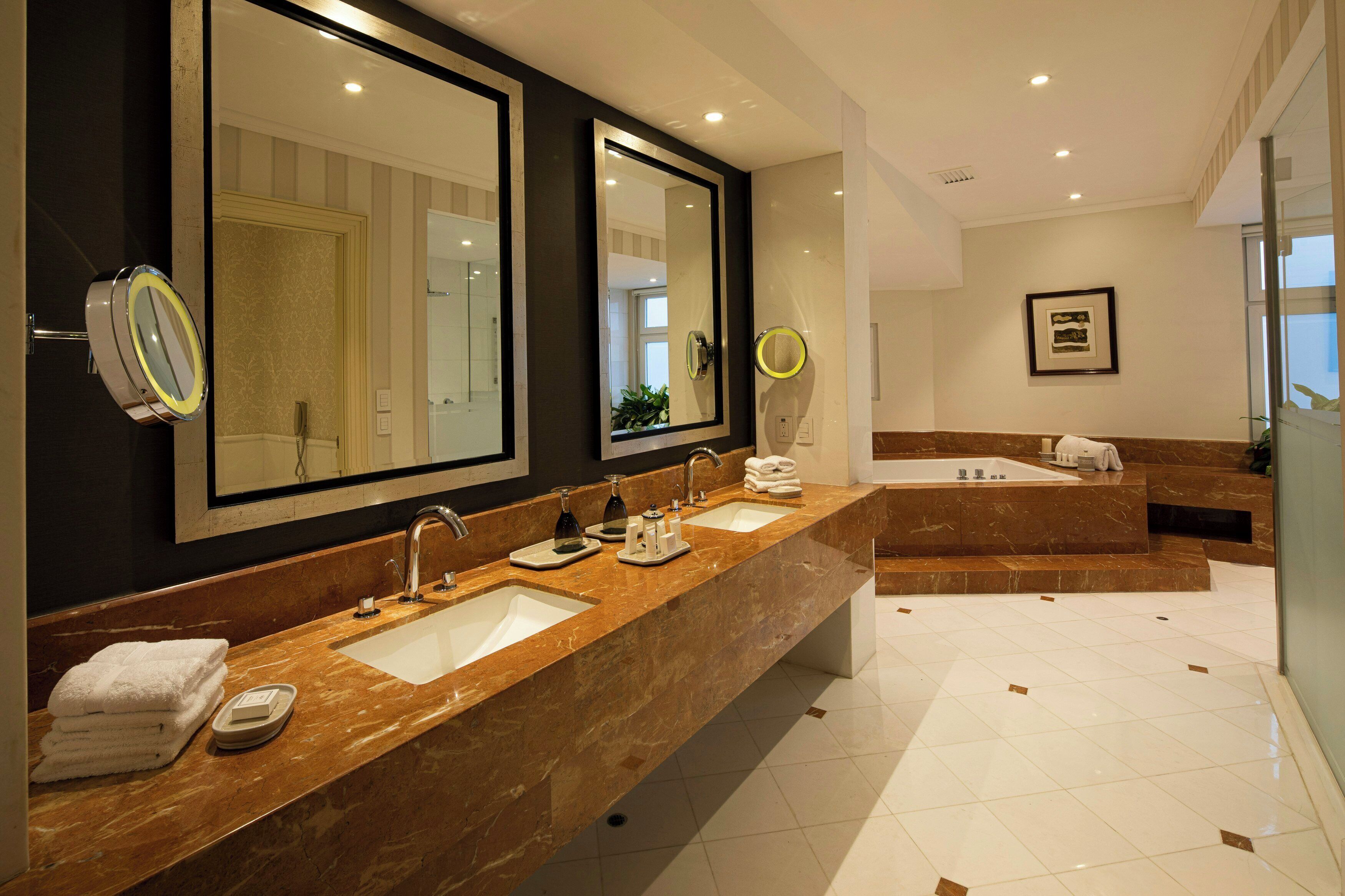 A modern bathroom with two sinks, large mirrors, and a separate shower area.
