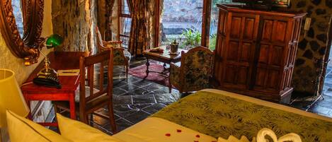 A hotel room with a bed, a desk with a lamp, a television on a cabinet, and a view of the outdoors through a window.