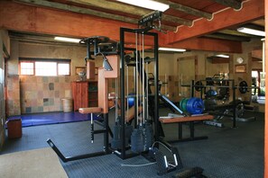 A gym with various exercise equipment, including a squat rack, benches, and weight stacks. - Misty Hills Country Hotel (Muldersdrift)
