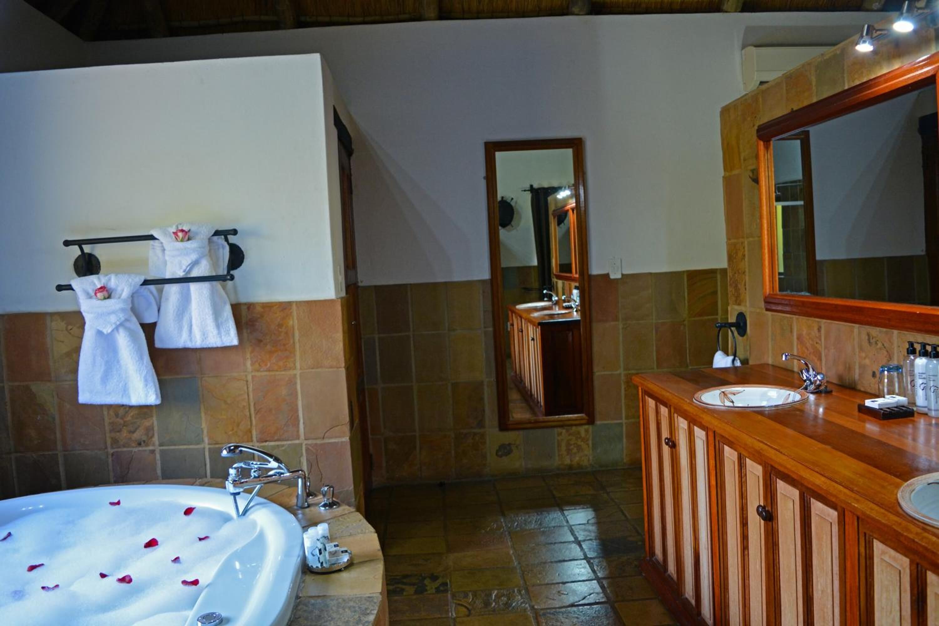 A bathroom with a large bathtub, two sinks, and a wooden vanity.