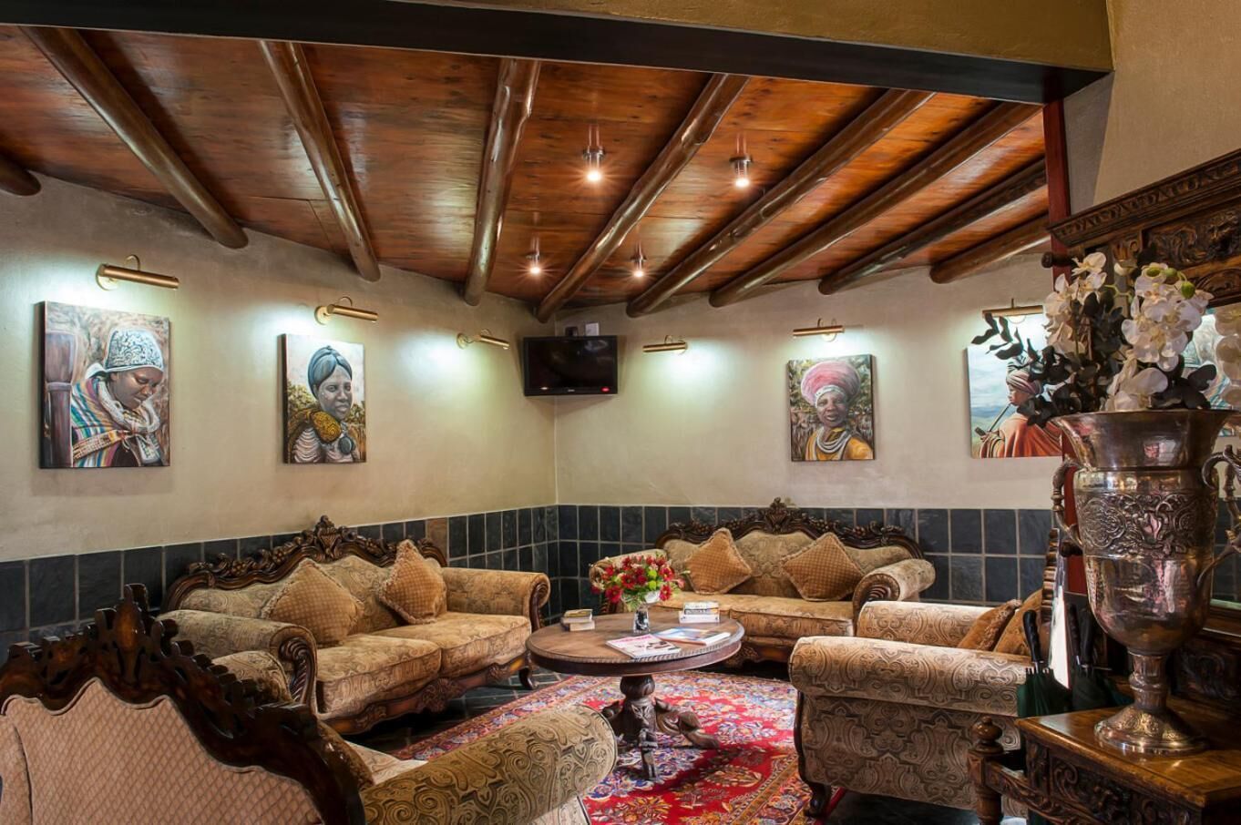 Una habitación tradicional con muebles ornamentados, un jarrón decorativo grande y obras de arte en las paredes.