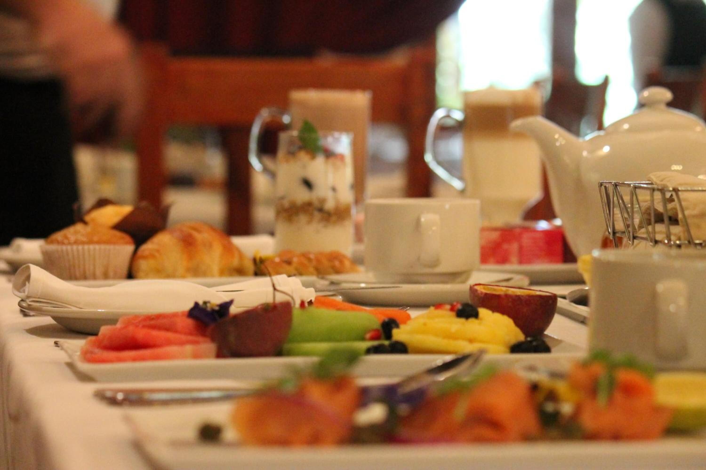 Une table de petit-déjeuner avec divers aliments, une théière et une tasse.