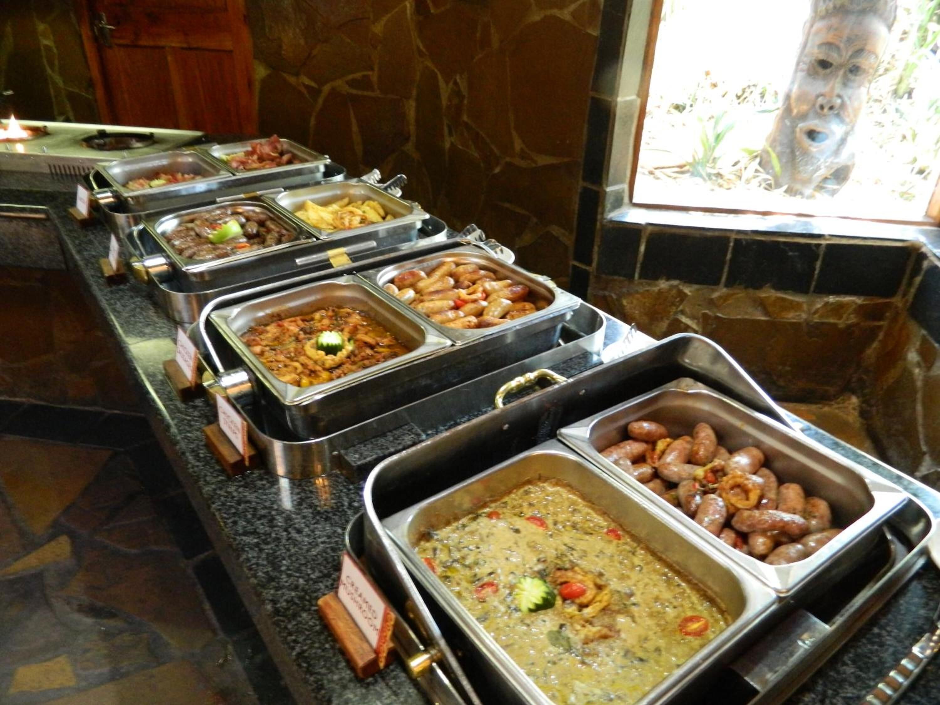A buffet with various food options, including meats, vegetables, and sauces.
