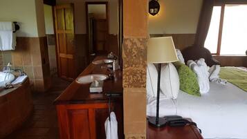 A hotel room with a wooden vanity, a bed with a green pillow, a lamp, and a telephone.
