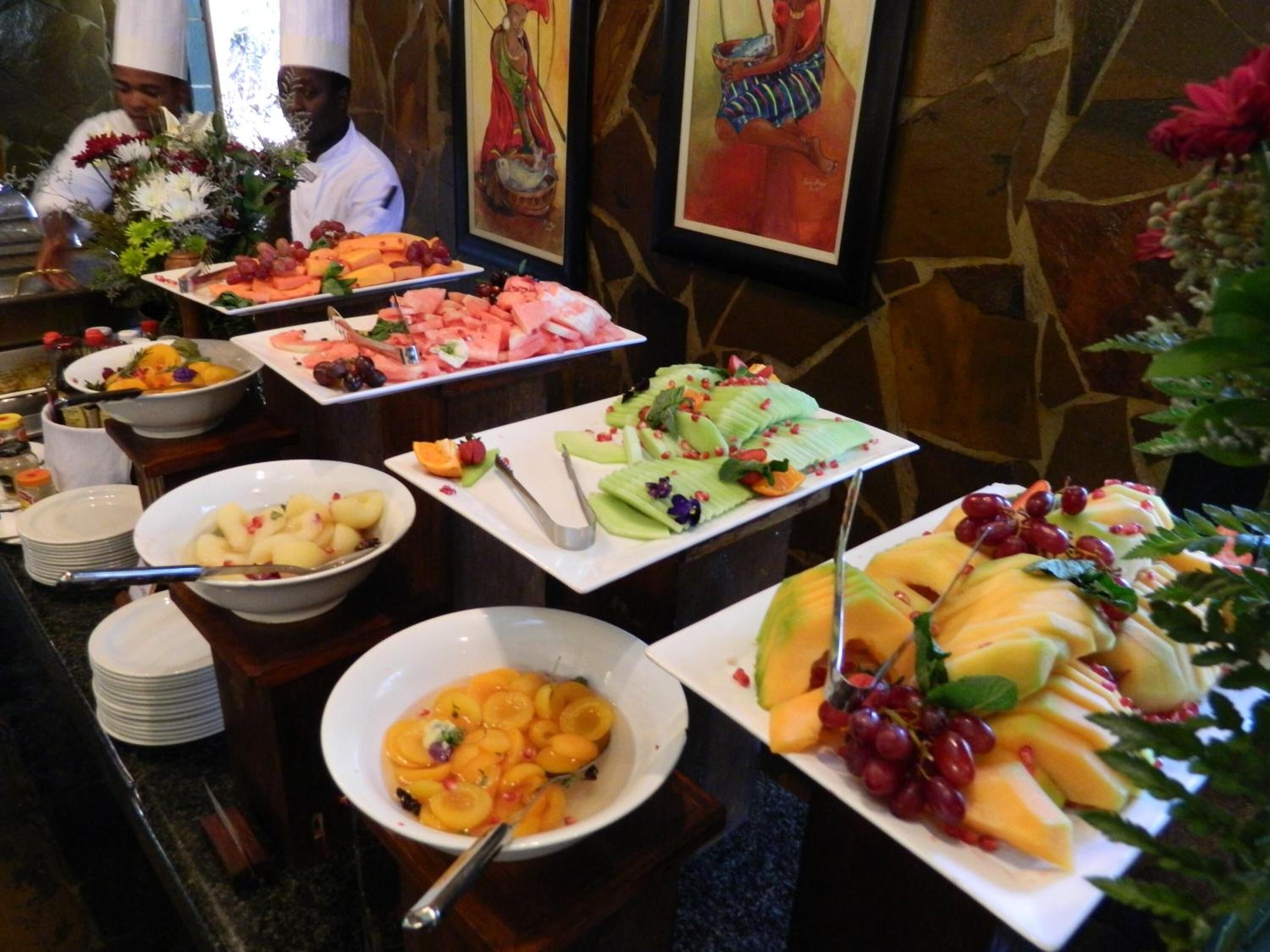 Un buffet con diverse varietà di frutta e verdura, tra cui anguria, uva e melone.
