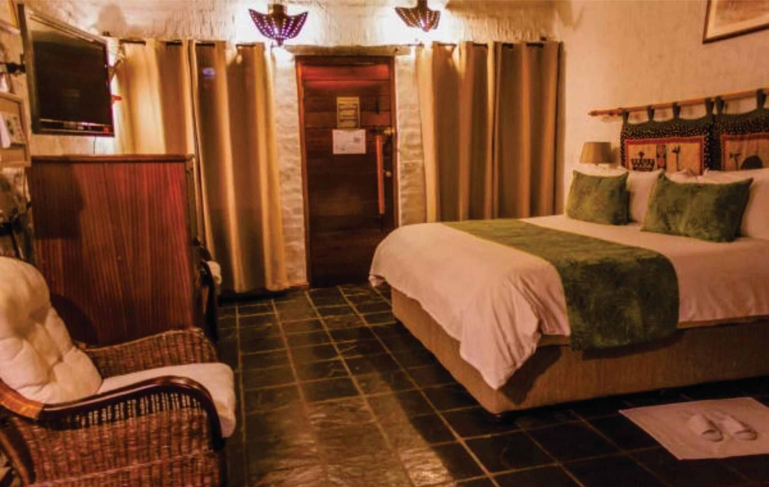 Een hotelkamer met een bed, een stoel, een televisie en gordijnen.