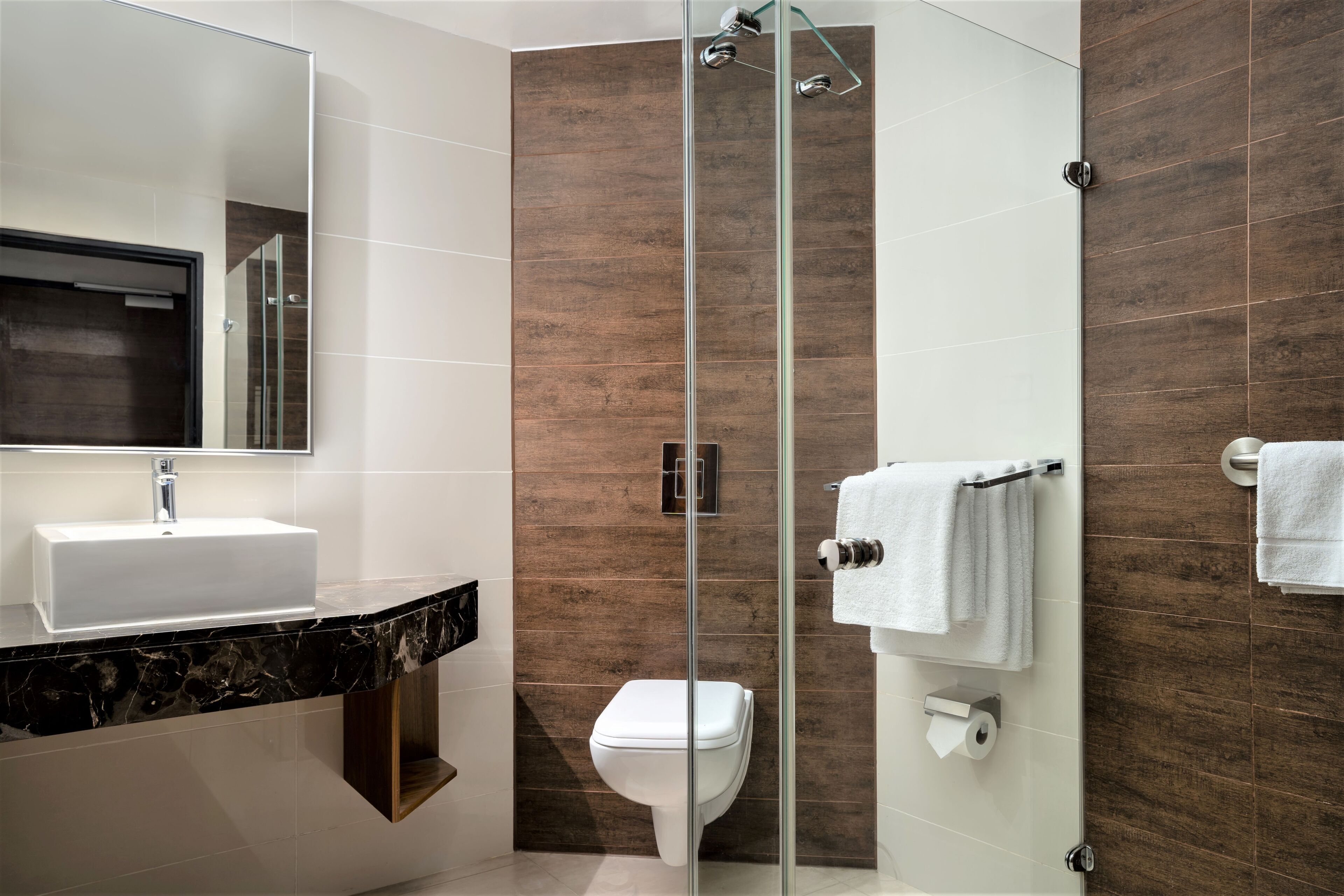 A modern bathroom with a glass-enclosed shower, a white sink, and a toilet.