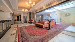 A spacious lobby with a large red carpet, a leather sofa, and a chandelier. - Premier Hotel Cape Town (Cape Town)