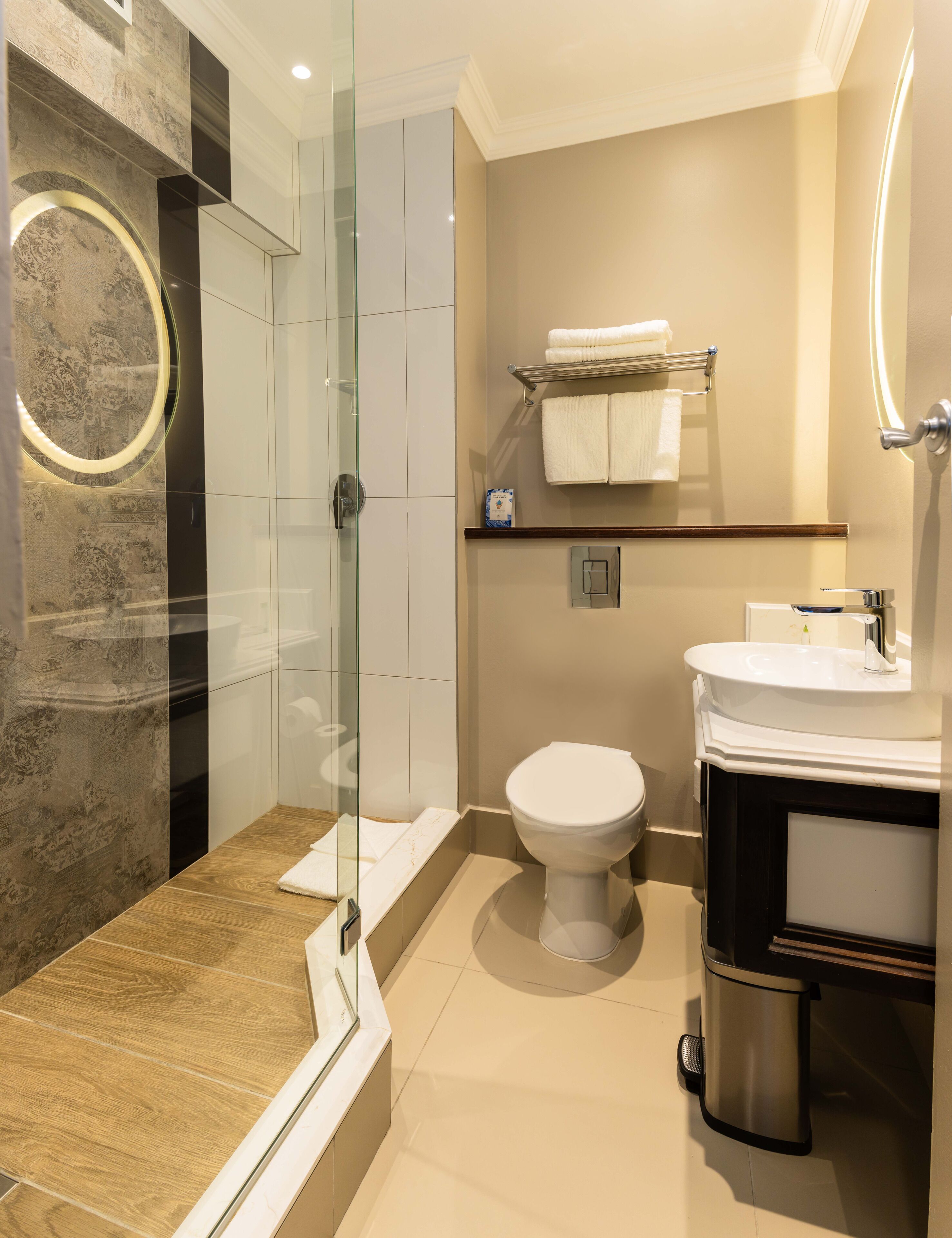 A modern bathroom with a glass-enclosed shower, a toilet, and a sink with a mirror.