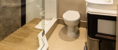 A modern bathroom with a glass-enclosed shower, a toilet, and a sink with a mirror.
