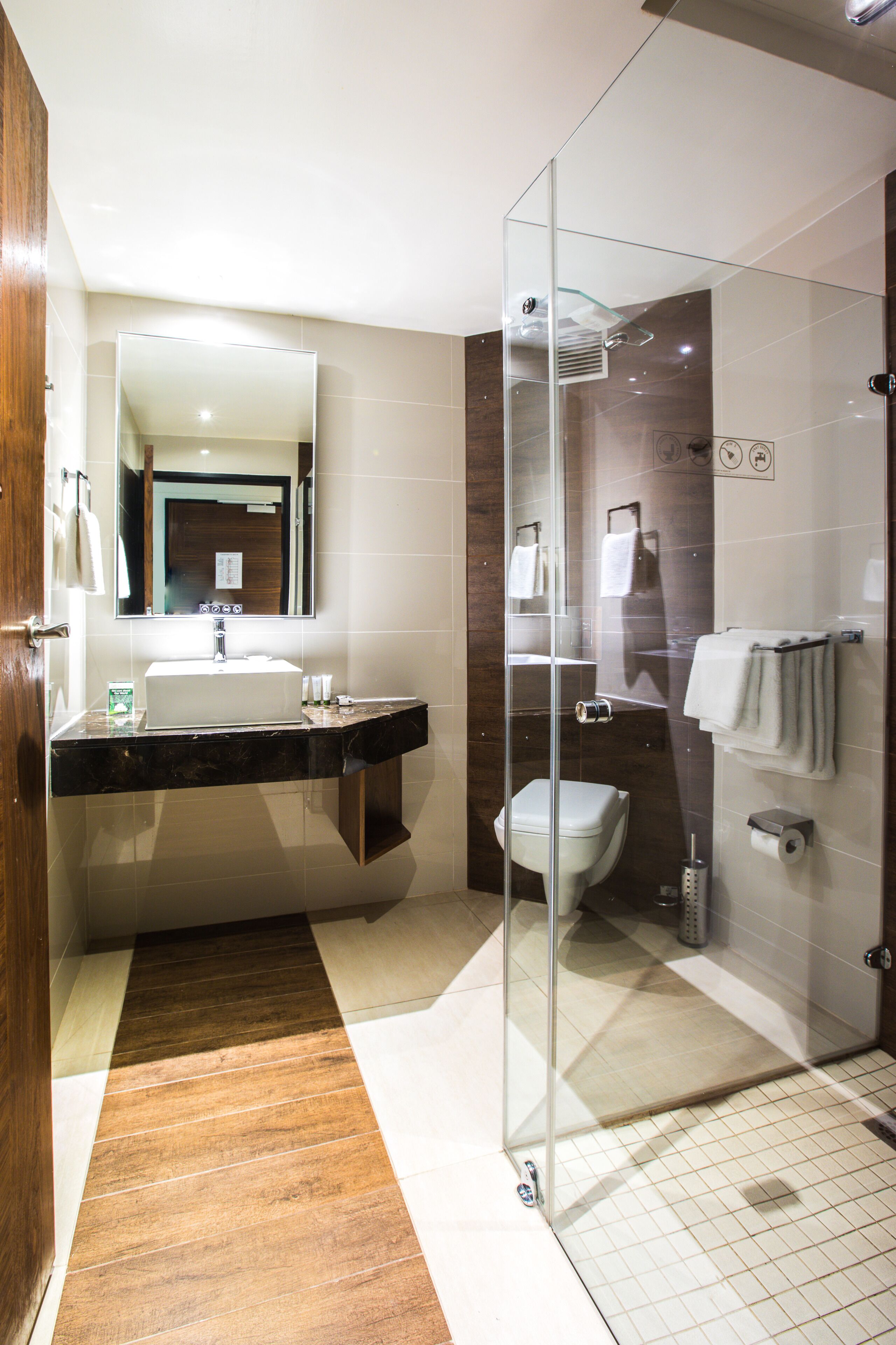 Een moderne badkamer met een douchecabine van glas, een wastafel met spiegel en een toilet.
