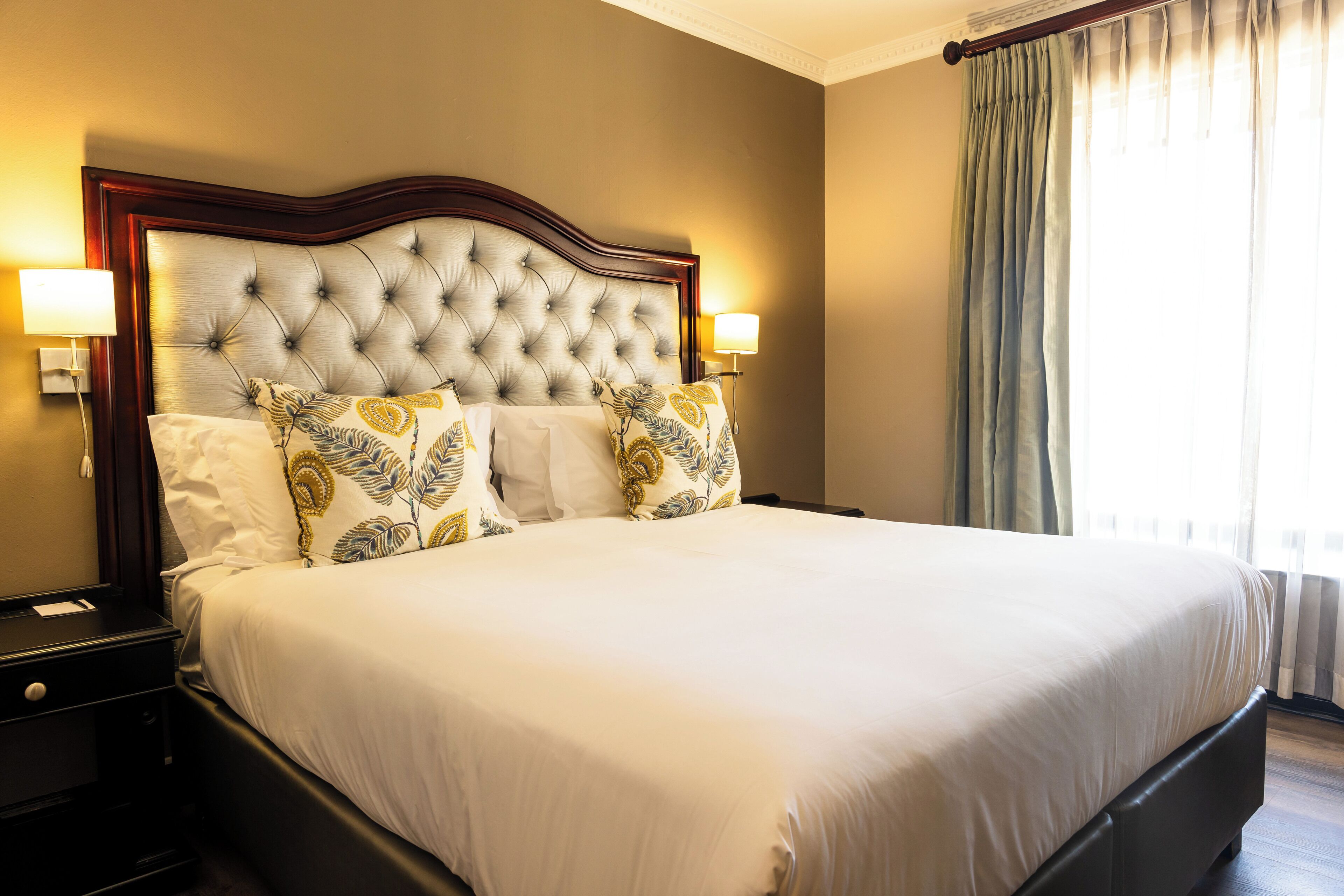 A large bed with a tufted headboard, two bedside lamps, and decorative pillows.