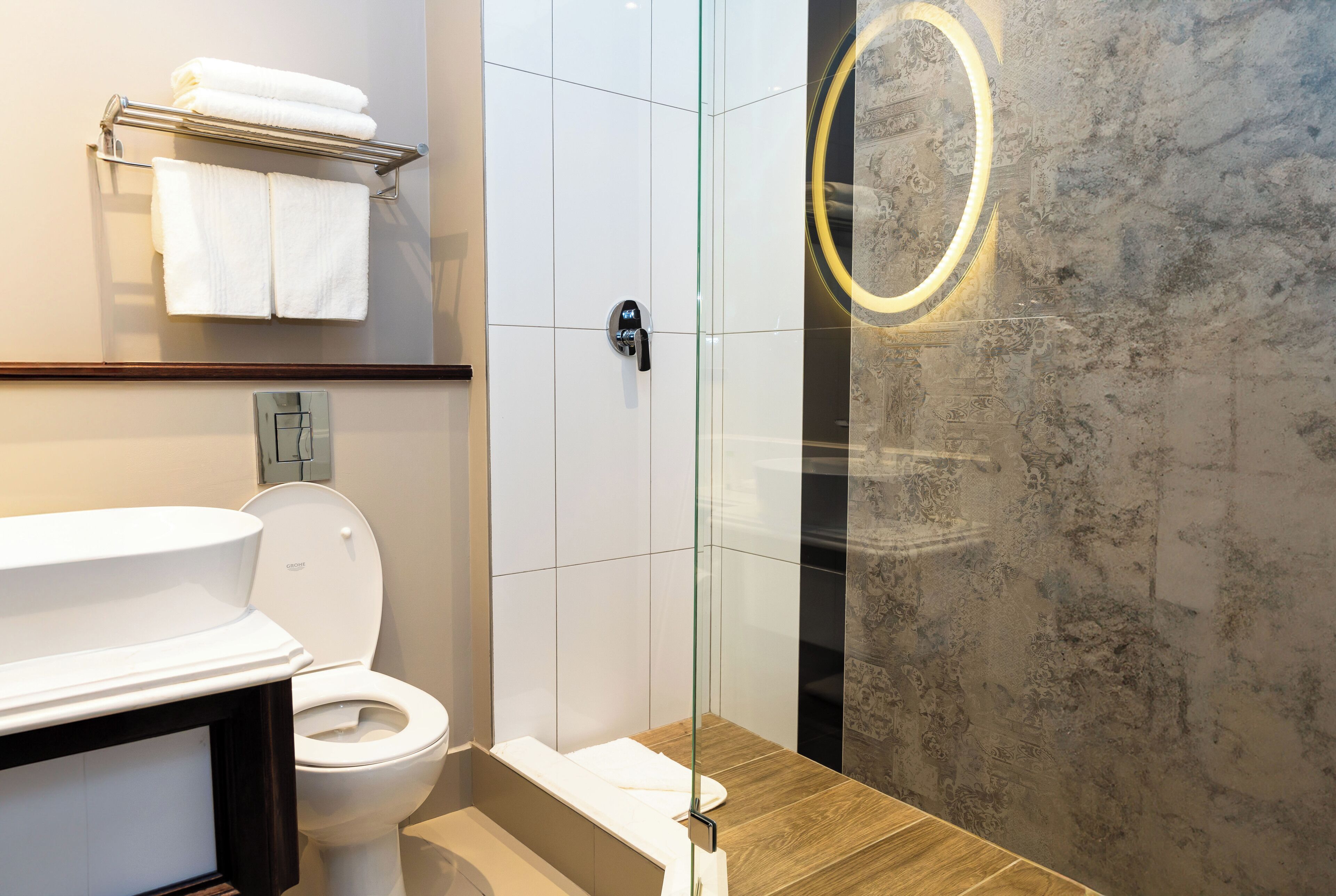 A modern bathroom with a toilet, a glass shower enclosure, and a wooden vanity.