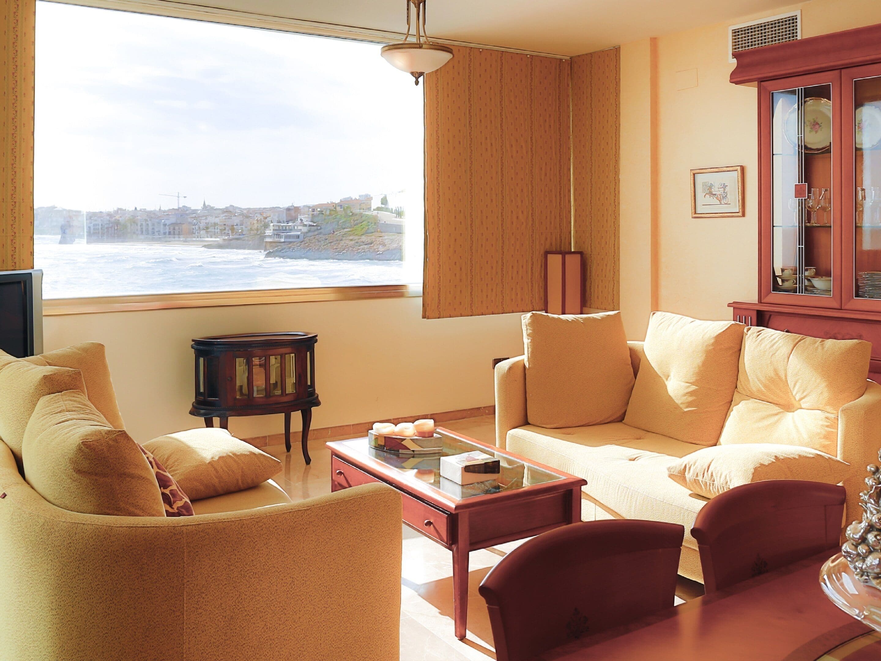 Un salon avec vue sur la mer, comprenant un canapé, une table basse et un meuble.