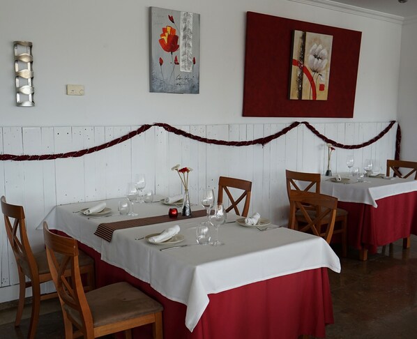 A dining area with tables set for a meal, chairs, and a decorative garland on the wall. - Hotel Port Sitges (Sitges)