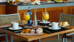 A breakfast table with croissants, pastries, and orange juice glasses.