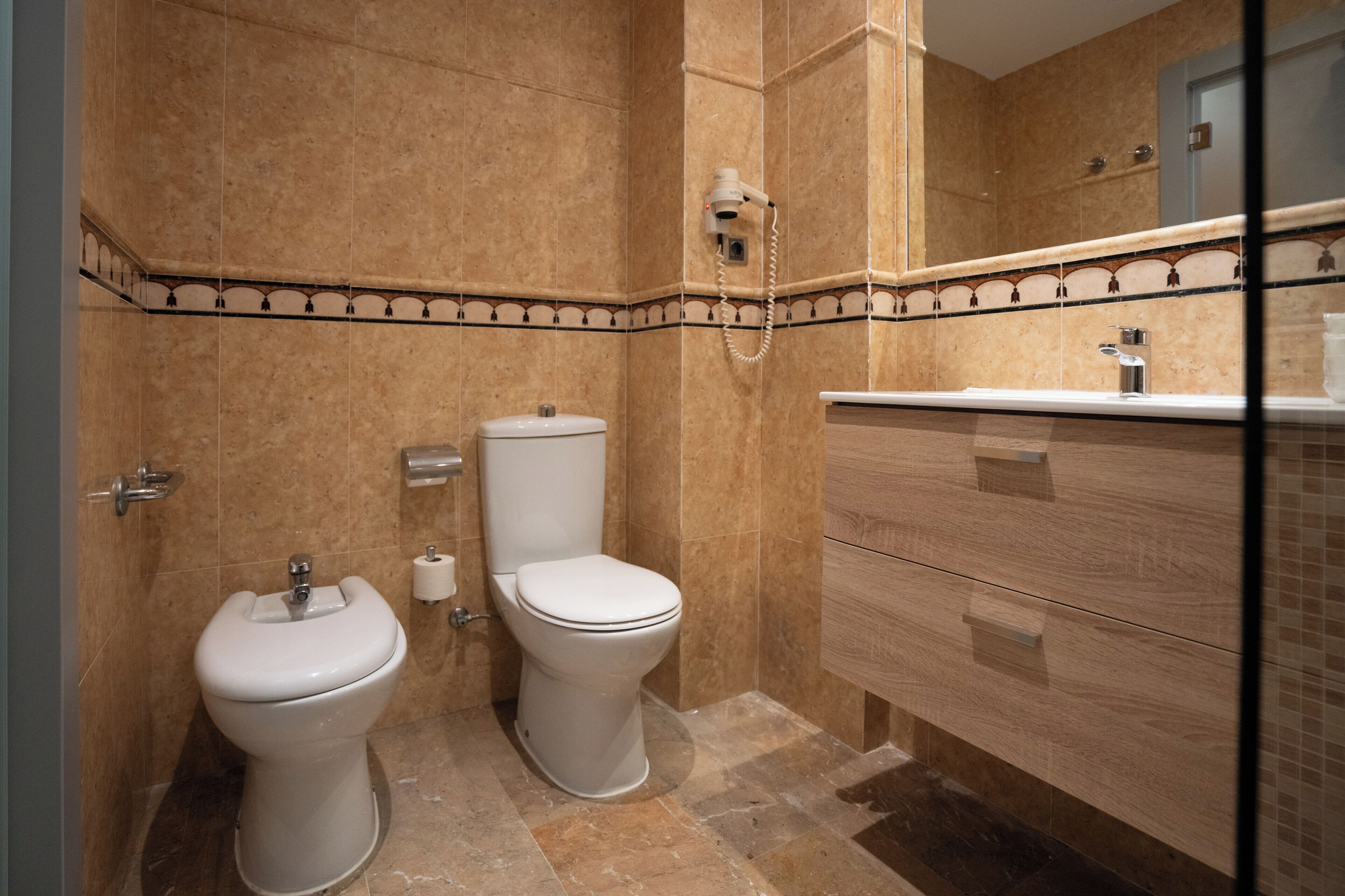 A bathroom with two toilets, a sink, and a mirror.