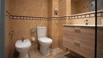 A bathroom with two toilets, a sink, and a mirror.