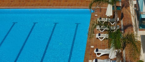 Una piscina al aire libre de temporada, sombrillas, tumbonas