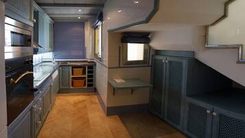 A compact kitchen with built-in appliances, a small window, and a unique architectural design.