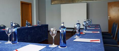 Een vergaderruimte met tafels klaar voor vergaderingen, voorzien van waterflesjes, glazen en notitieblokken.