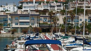 A marina with multiple boats docked, surrounded by residential buildings with balconies and terraces.