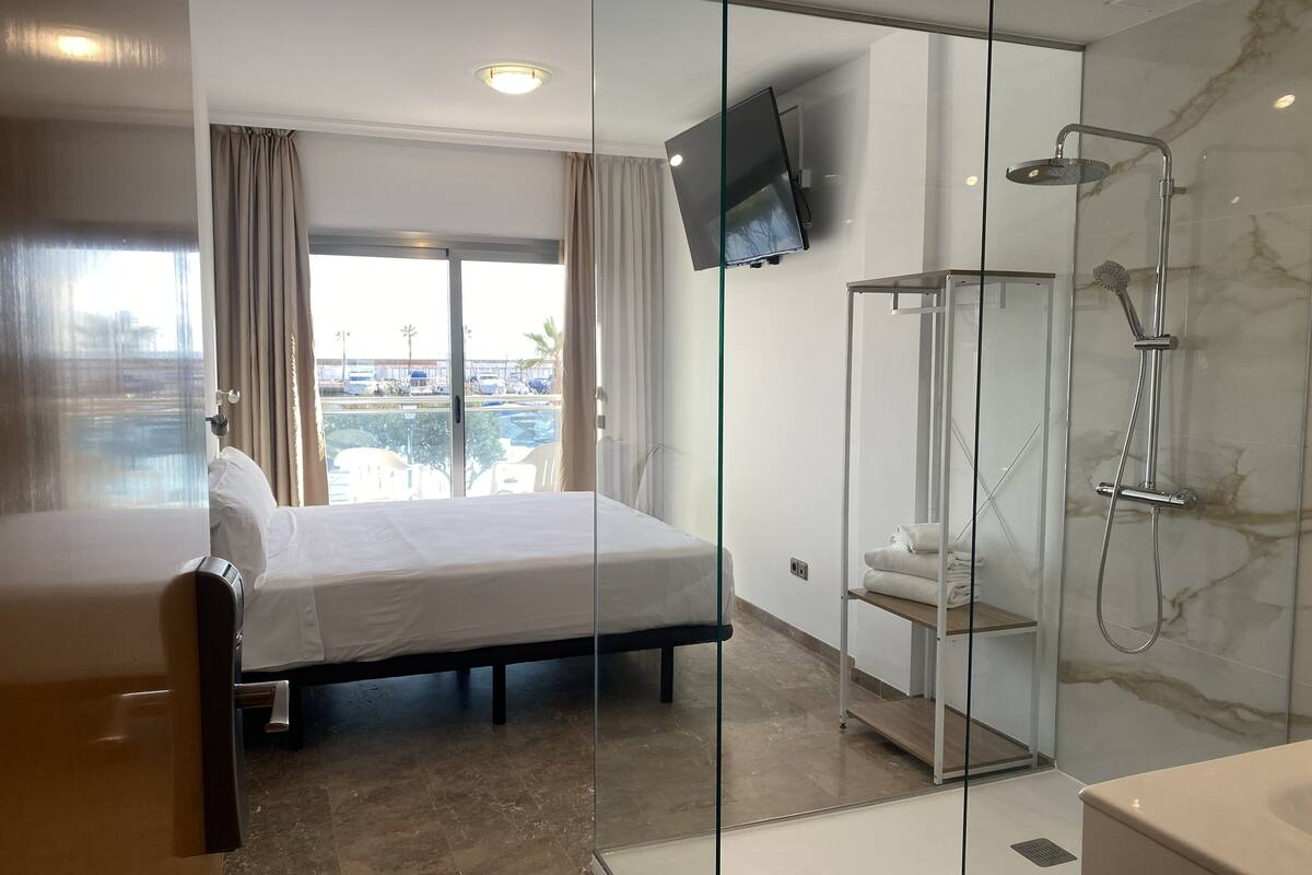 A hotel room with a bed, a shower, and a TV mounted on the wall.